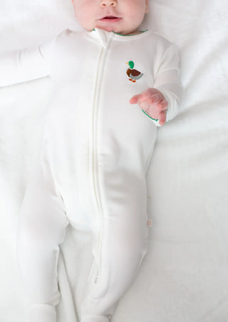 Baby in a white onesie with a small design on a white background