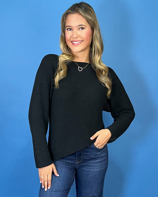 Black long sleeve knit sweater with a classic round neckline, subtle textured finish, relaxed fit, and slightly curved hem.