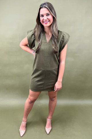 Woman wearing an olive green dress against a matching background
