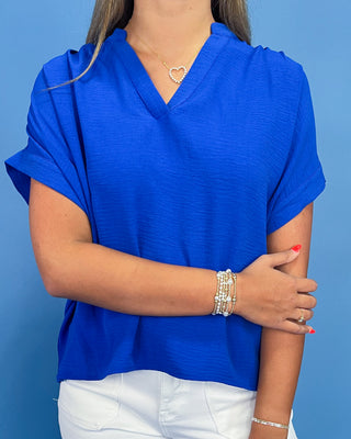 Person wearing a blue top with white pants against a blue background