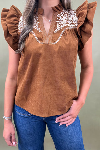Rust brown corduroy blouse with ruffled sleeves and white floral embroidery paired with dark wash wide-leg jeans for a chic fall look