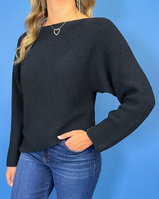 Black long sleeve knit sweater with a classic round neckline, subtle textured finish, relaxed fit, and slightly curved hem.