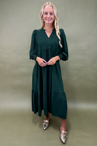 Woman wearing a dark green dress against a plain background