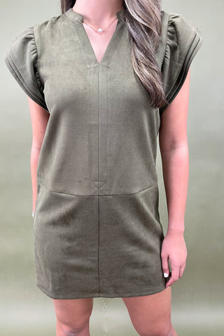 Person wearing a green dress against a neutral background