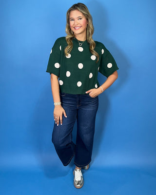 Forest green short sleeve knit sweater with oversized ivory polka dots, a classic crew neckline, ribbed trim, and a relaxed fit.