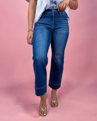 Person wearing blue jeans on a pink background