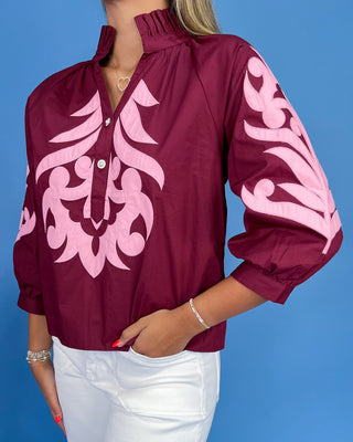 Maroon blouse with pink floral patterns on a blue background