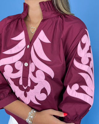 Maroon jacket with pink floral patterns on a blue background