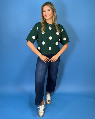 Forest green short sleeve knit sweater with oversized ivory polka dots, a classic crew neckline, ribbed trim, and a relaxed fit.