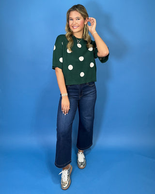 Forest green short sleeve knit sweater with oversized ivory polka dots, a classic crew neckline, ribbed trim, and a relaxed fit.