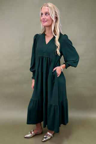 Woman wearing a dark green dress against a plain background