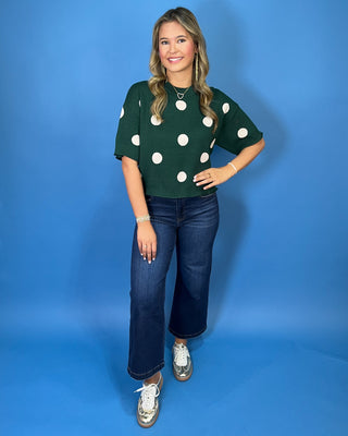Forest green short sleeve knit sweater with oversized ivory polka dots, a classic crew neckline, ribbed trim, and a relaxed fit.