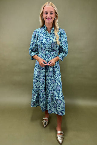 Woman wearing a blue floral dress against a beige background