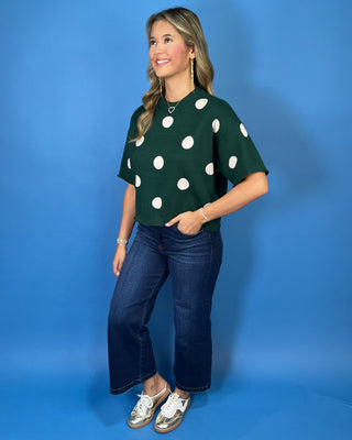 Forest green short sleeve knit sweater with oversized ivory polka dots, a classic crew neckline, ribbed trim, and a relaxed fit.