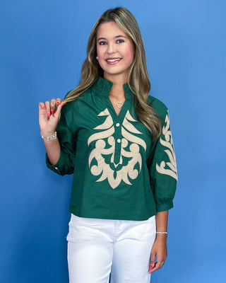 Woman wearing a green blouse with a white pattern against a blue background
