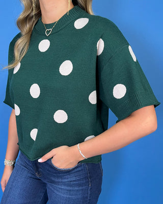 Forest green short sleeve knit sweater with oversized ivory polka dots, a classic crew neckline, ribbed trim, and a relaxed fit.