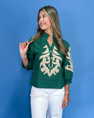 Woman wearing a green blouse with white patterns against a blue background