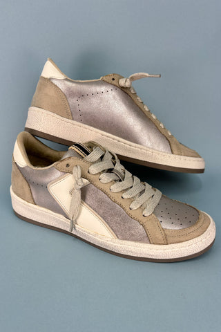 Pair of beige and brown sneakers on a gray background