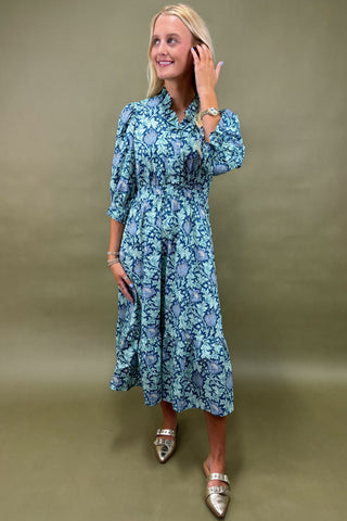 Woman wearing a blue floral dress against a beige background