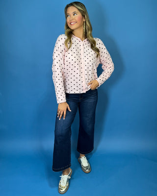 Light pink button-front knit cardigan with chocolate brown polka dots, a round neckline, long sleeves, and a relaxed fit.