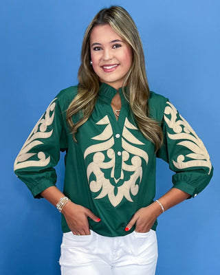 Woman wearing a green blouse with white patterns against a blue background