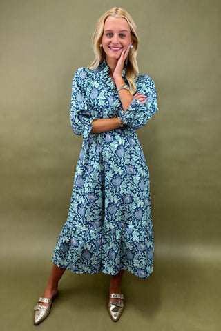 Woman wearing a blue floral dress against a green background