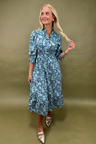 Woman wearing a blue floral dress against a green background