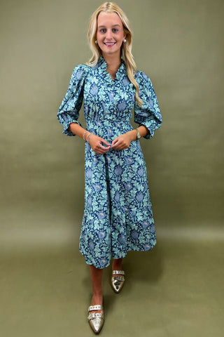 Woman wearing a blue floral dress against a green background