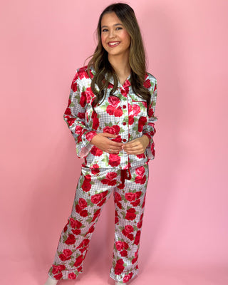 Woman wearing a red and white floral pajama set on a pink background