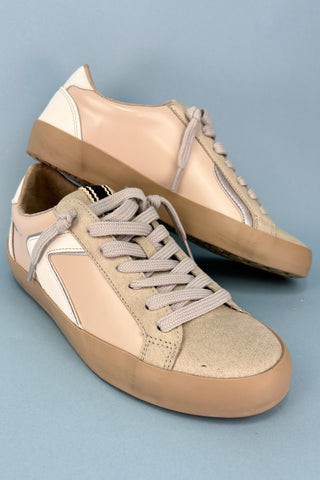 Pair of beige and brown sneakers on a light blue background