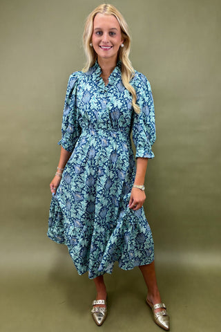 Woman wearing a blue floral dress against a green background