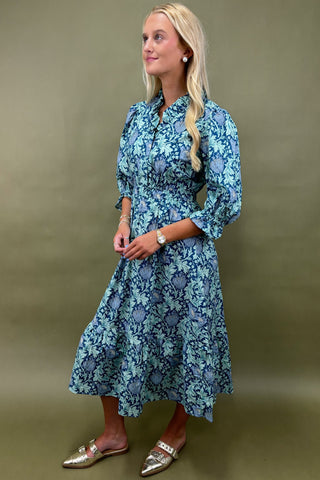 Woman wearing a blue floral dress against a green background