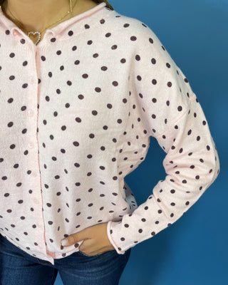 Light pink button-front knit cardigan with chocolate brown polka dots, a round neckline, long sleeves, and a relaxed fit.
