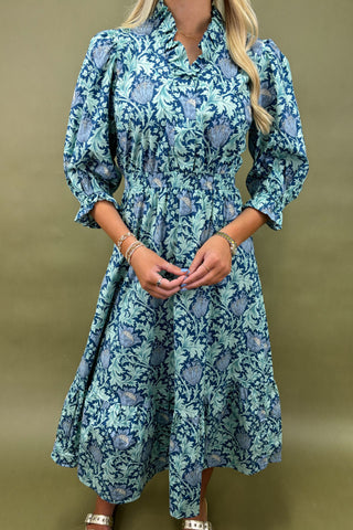 Woman wearing a blue floral dress against a green background