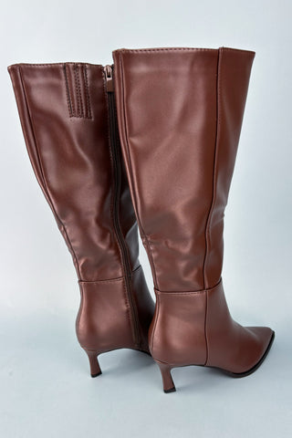 Pair of brown knee-high boots on a light gray background