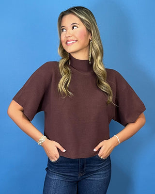 Chocolate brown short sleeve mock neck knit sweater with a subtle textured finish, relaxed fit, and wide sleeves.