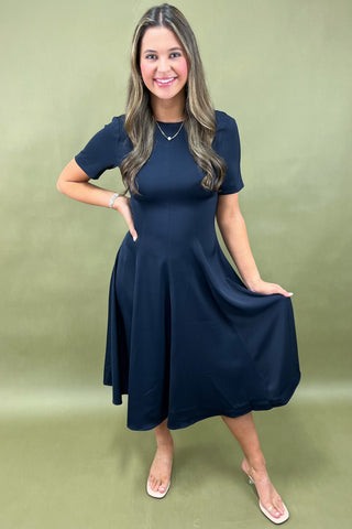 Woman wearing a navy blue dress against a green background