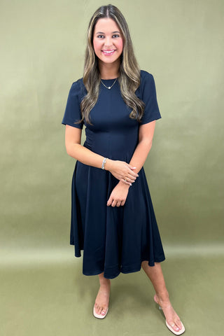 Woman wearing a navy blue dress against a green background