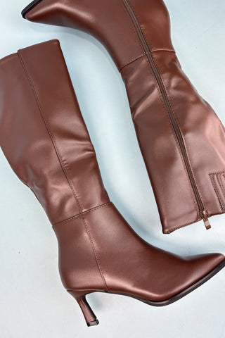 Pair of brown leather knee-high boots on a light gray background