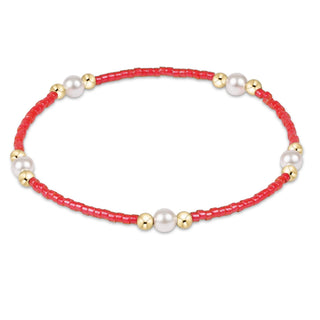 Bracelet with red beads, gold accents, and pearls on a white background