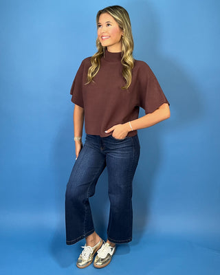 Chocolate brown short sleeve mock neck knit sweater with a subtle textured finish, relaxed fit, and wide sleeves.