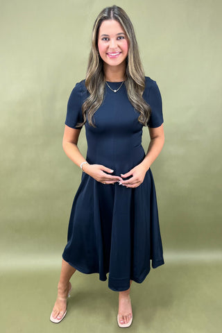 Woman wearing a navy blue dress against a green background