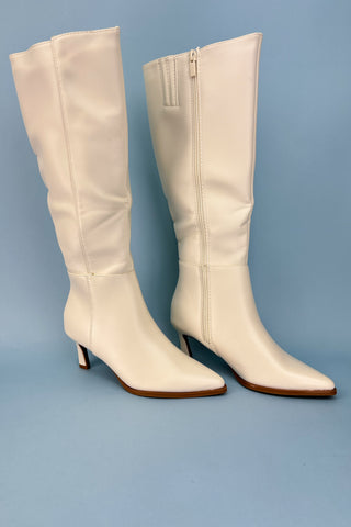 Pair of white knee-high boots on a blue background