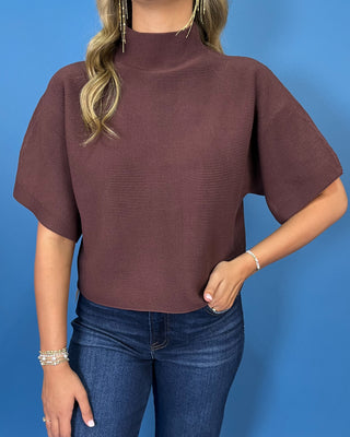 Chocolate brown short sleeve mock neck knit sweater with a subtle textured finish, relaxed fit, and wide sleeves.