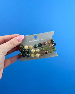Shop the Olive Multi-Colored Beads Bracelet Set featuring glossy green, brown, and cream marbled beads with gold-tone accents for effortless everyday style.