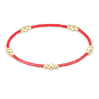 Bracelet with red beads and gold accents on a white background