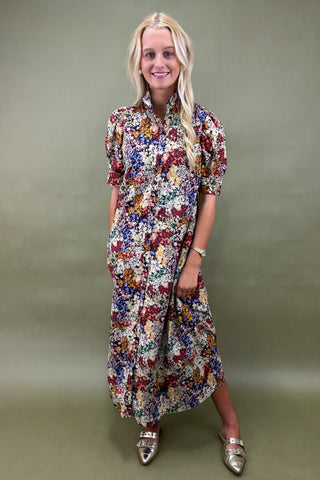 Woman wearing a colorful floral dress against a plain background