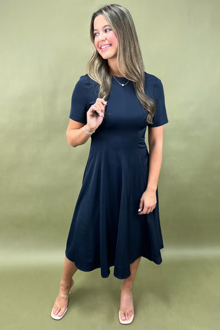 Woman wearing a navy blue dress against a green background