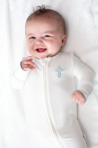 Baby wearing a white onesie with a blue cross design on a white background