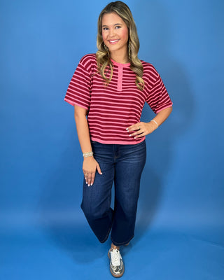Pink and burgundy striped short sleeve knit top with a round neckline, button placket, relaxed fit, and contrast pink trim.